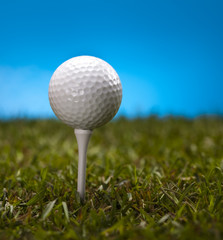  Golf ball on green grass over a blue background 