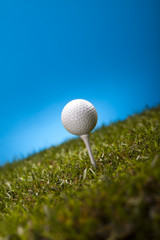  Golf ball on green grass over a blue background 