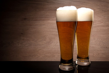 Two glasses with beer served on the table.