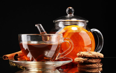 Glass teapot and cup with black fruit tea and cookies isolated