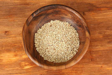 Raw buckwheat in wooden bowl on table on brown background