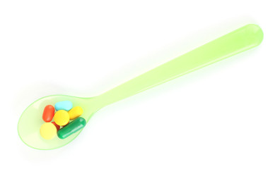 Plastic spoon with color pills, isolated on white