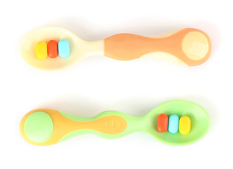 Plastic spoons with color pills, isolated on white