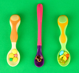 Plastic spoons with color pills, on green background