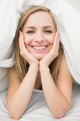 Fototapeta na wymiar Close-up portrait of beautiful woman under sheet in bed