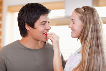 Woman feeding vegetable to man