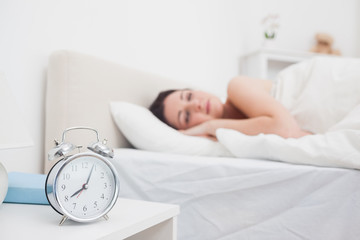 Woman sleeping in bed with focus on alarm clock