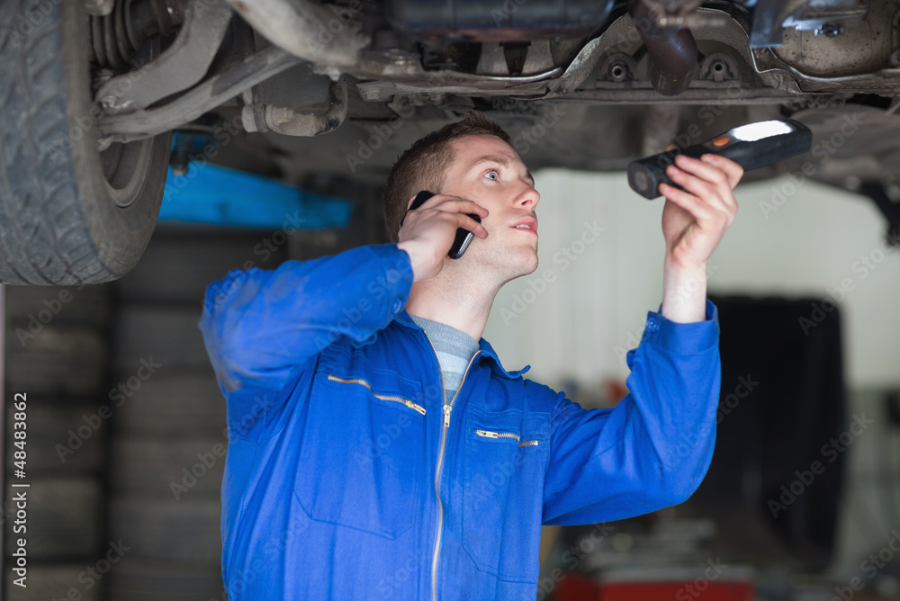 Poster mechanic on call while examining car