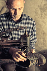 Caucasian senior craftsman works workshop fixes shoes. traditional manual labor