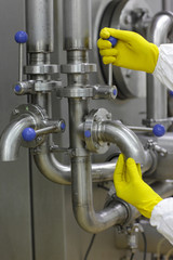 hands in yellow gloves on tap and lever of technological system