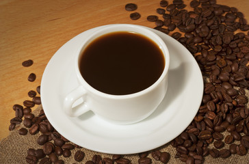 A cup of hot coffee with a lot of coffee beans