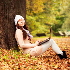 Pretty student girl with laptop in autumn park. Young Teenager - 48497857