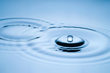 Water drop falling into water making a perfect droplet splash