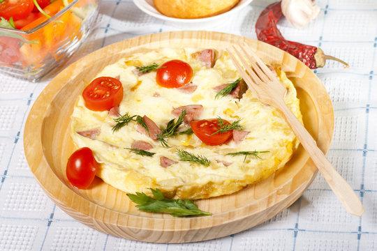 omelet with tomatoes on wooden plate