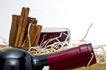 red wine bottle with a glass and cinnamons