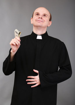 Young Pastor With Money On Gray Background