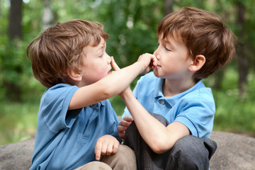 Two brothers click on  nose