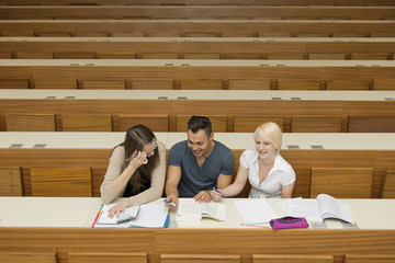 Ein Student und zwei Studentinnen lernen gemeinsam im Hörsaal