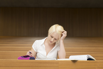 Eine junge blonde Studentin lernt alleine im Hörsaal