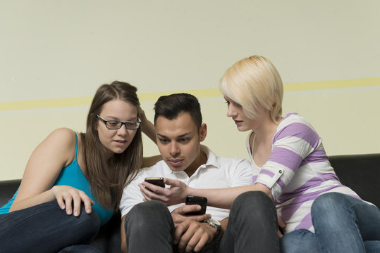 Drei Studenten kommunizieren und spielen mit ihren Handys