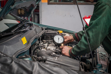 Mechanik diagnozujący usterkę silnika w warsztacie samochodowym - obrazy, fototapety, plakaty