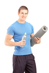 Male holding a bottle of refreshment drink and a mat after an ex