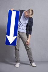 Sad man holding direction arrow sign pointing down. - obrazy, fototapety, plakaty