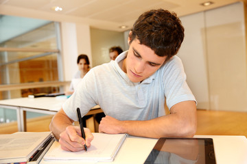 Portrait of student boy writing on notebook