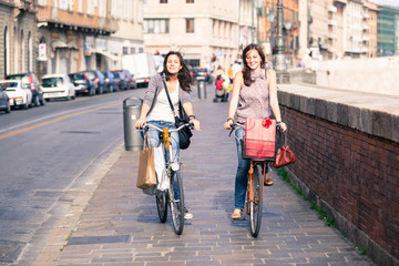 Obraz na płótnie Canvas Dwie piękne kobiety Walking w mieście z rowerami i toreb