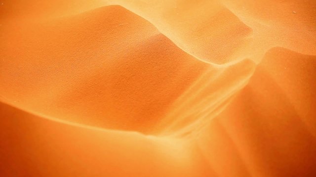 Sand blowing from golden dunes in desert