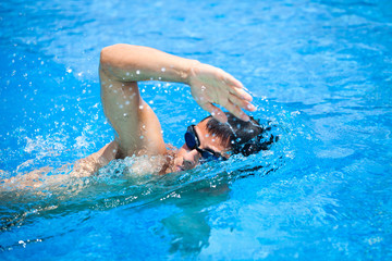 Obraz na płótnie Canvas Młody człowiek pływanie przednią indeksowania w basenie