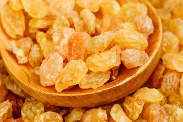 Golden raisins close- up and wooden spoon, food background
