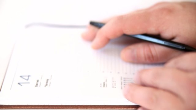 Man writing information in agenda book