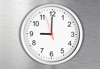 Classical clock on metal background displaying nine o'clock