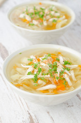 two bowls of vegetable soup with chicken and parsley
