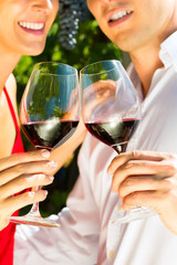 Woman and man in vineyard drinking wine