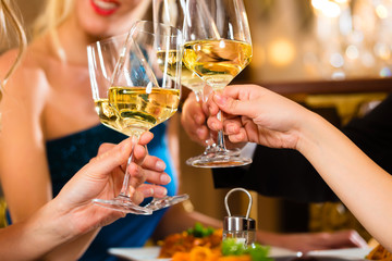 Friends in a very good restaurant clink glasses