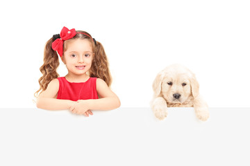 A small cute girl and labrador retriever posing behind a panel