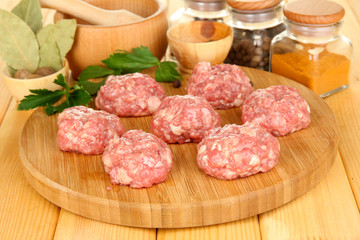 Raw meatballs with spices on wooden table