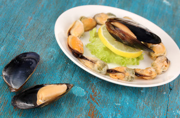 Snack of mussels and lemon on plate on blue wooden table