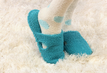 Female legs in color slippers, on carpet background