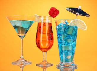 Alcoholic cocktails with ice on orange background