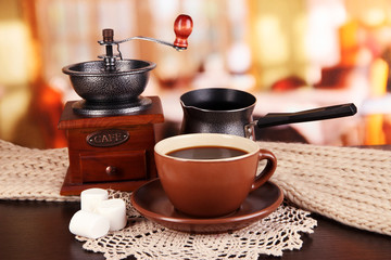 cup of coffee with scarf and coffee mill on table in room