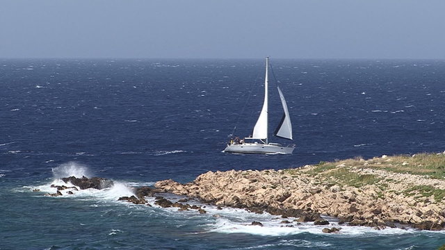 Sailboat passing by small island