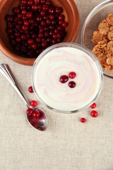 Glass of yoghurt dessert with berries, on tablecloth background