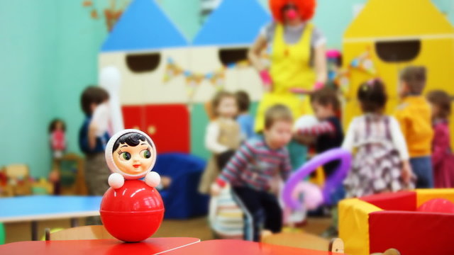 roly-poly toy on table, behind children playing with clown