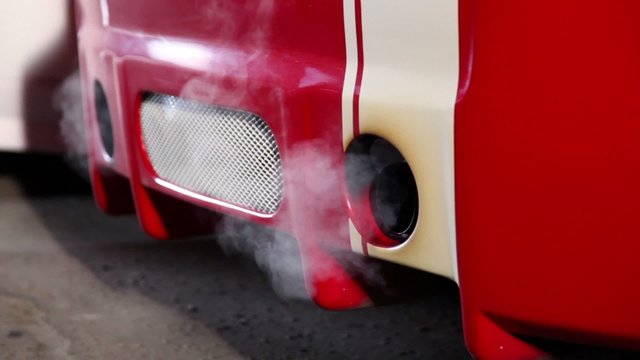 Smoke goes from tube of car with colorful sport design at night