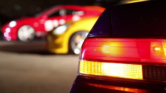 Red automobile rides backward to row of several cars
