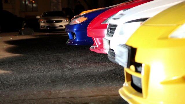 Red automobile rides backward to row of several cars