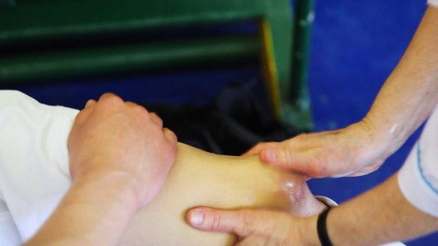 sports doctor does massage injured knee of sportsman